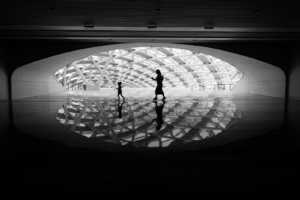 Two people silhouetted against a bright, modern ceiling.